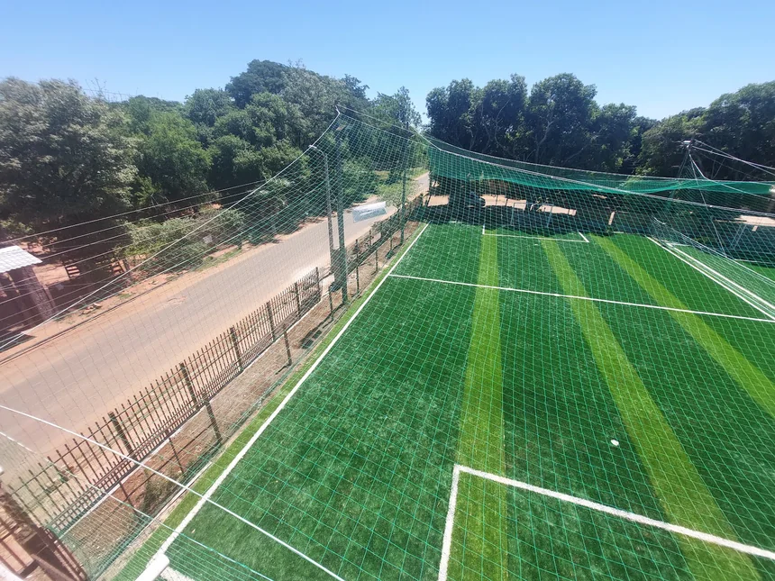 La cancha sintética, con las líneas recién pintadas y red alrededor, al lado de la calle